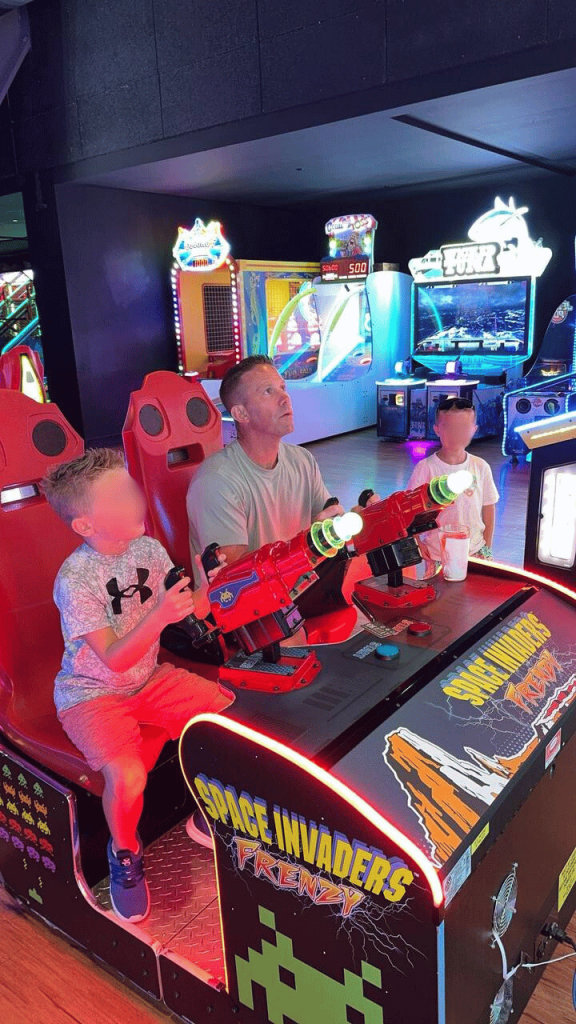 Happy children with their father playing in an arcade.